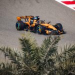 Mașină de Formula 1 McLaren pe circuit în timpul testelor, condusă de Oscar Piastri, cu accent pe performanță și tehnologie în competițiile auto.