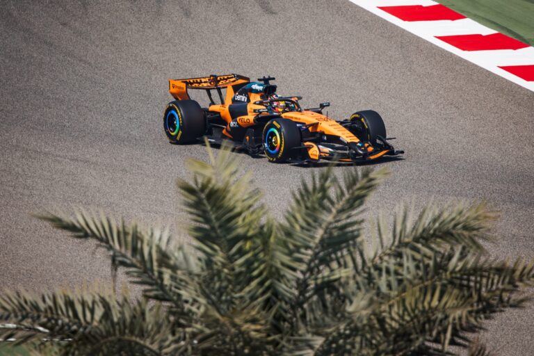 Mașină de Formula 1 McLaren pe circuit în timpul testelor, condusă de Oscar Piastri, cu accent pe performanță și tehnologie în competițiile auto.