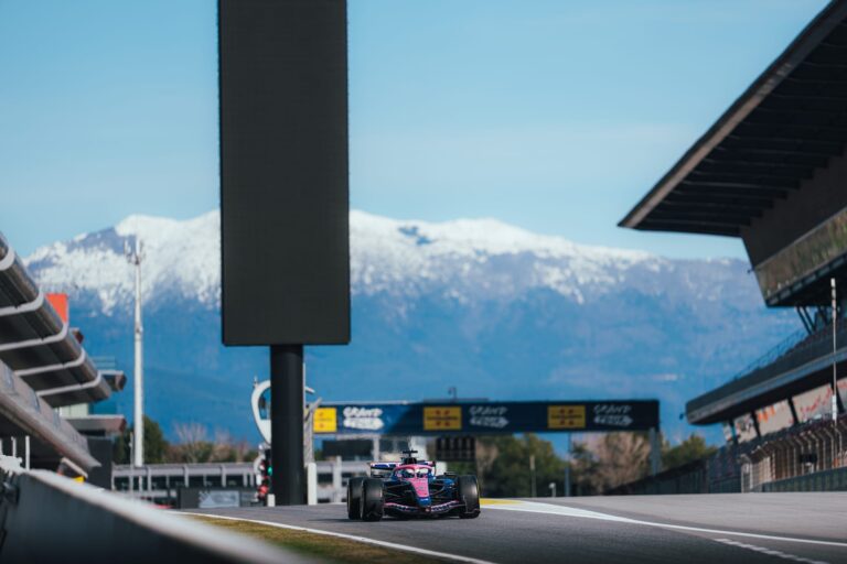 Circuitul de Formula 1 din Barcelona în timpul unei sesiuni de teste, cu mașini de curse pe pistă și infrastructura specifică competițiilor auto.