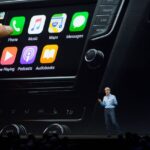 Interfața Apple CarPlay pe ecranul unui automobil, ilustrată în contextul influenței adoptării iOS 26 asupra vânzărilor Tesla.