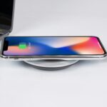 Dispozitiv de încărcare wireless pentru telefoane moderne, ilustrat cu un telefon plasat pe suportul de încărcare.