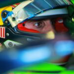 Pilot Red Bull purtând cască colorată în albastru, roșu și galben, specifică echipei, în timpul unei curse sau sesiuni de teste în Formula E.
