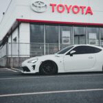 Logo-ul Toyota afișat pe un fundal neutru, ilustrând designul modern cu trei elipse care se intersectează, simbolizând istoria și valorile brandului.