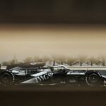 Mașină de curse Cadillac V-Series.R pe circuit, în timpul testelor pentru Formula 1, cu design aerodinamic și culori distinctive.