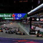 Cursă de Formula 1 noapte, mașini de curse pe pistă iluminată, branduri Heineken și TAG Heuer