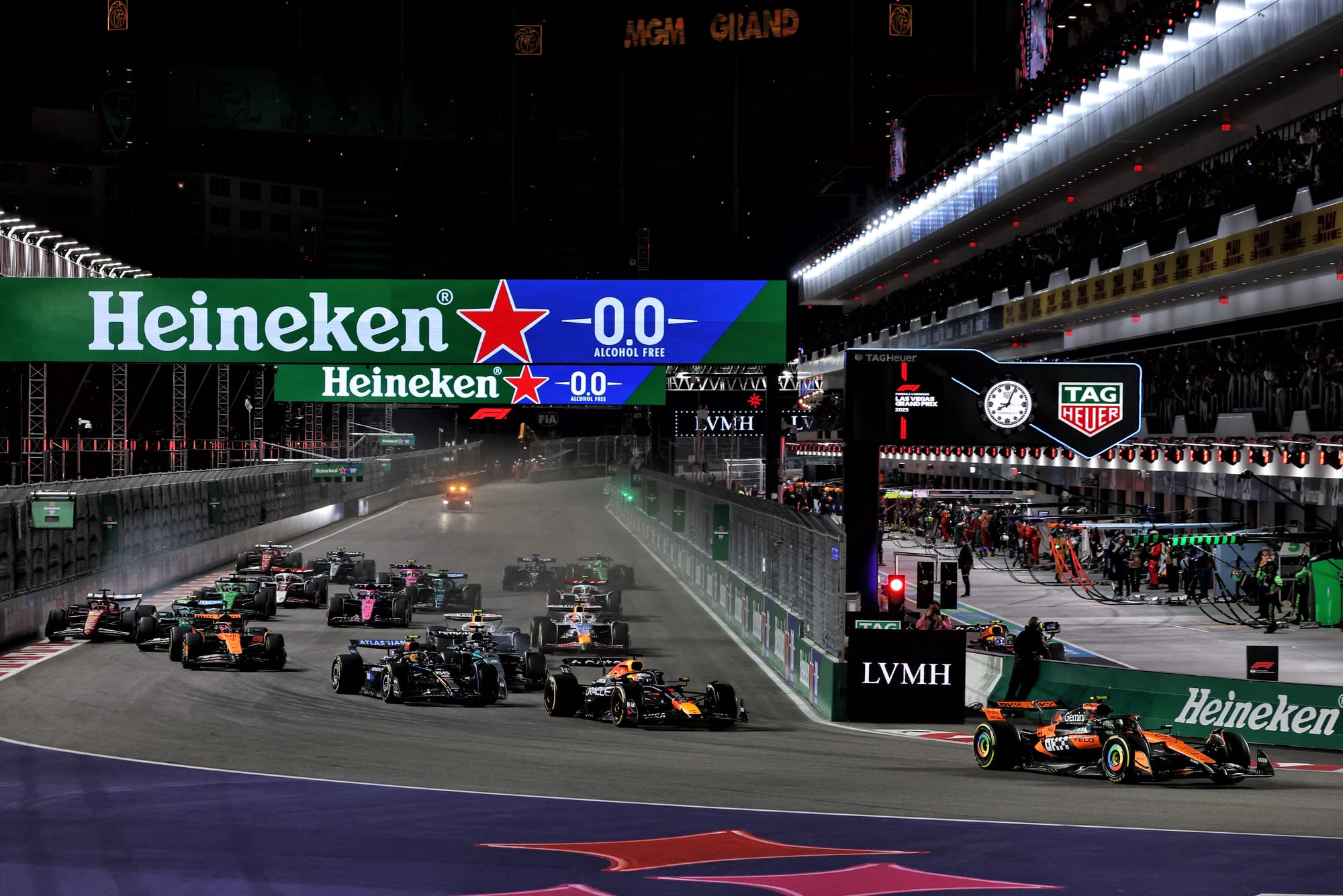 Cursă de Formula 1 noapte, mașini de curse pe pistă iluminată, branduri Heineken și TAG Heuer